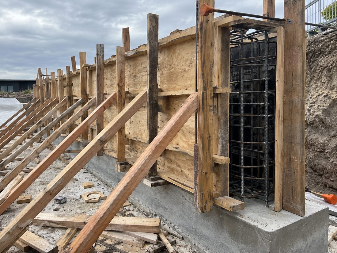 Braced plywood formwork and a steel reinforcing cage ready for a poured concrete retaining wall